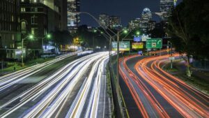 Boston, Massachusetts, USA skyline at night, featuring car lights trails on the foreground and illuminated buildings on the background